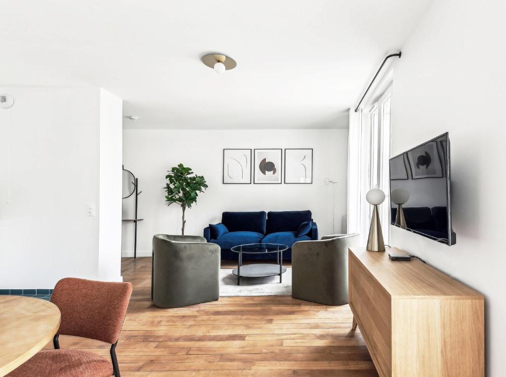un salon avec un canapé bleu et une table dans l'établissement Appartements Mairie de Pantin, à Pantin