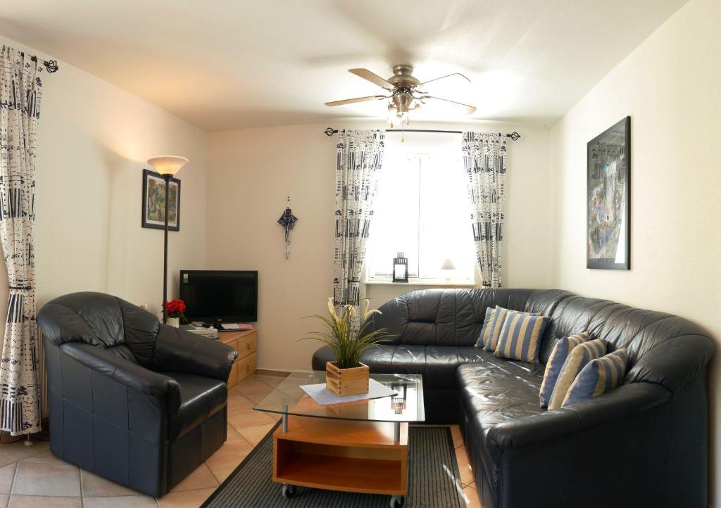 a living room with a leather couch and a table at Achtern Diek Haus 12c Wohnung 4 in Müggenburg