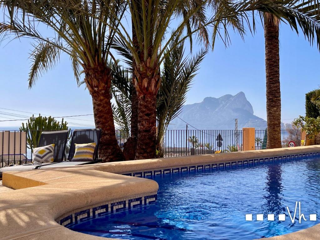 a pool with palm trees and a mountain in the background at VH CostaBlanca - EVA in Benissa