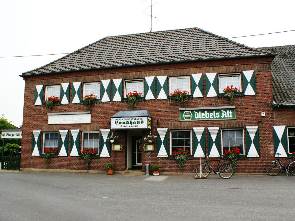 un edificio de ladrillo con banderas verdes y blancas. en Landhaus Spickermann, en Xanten