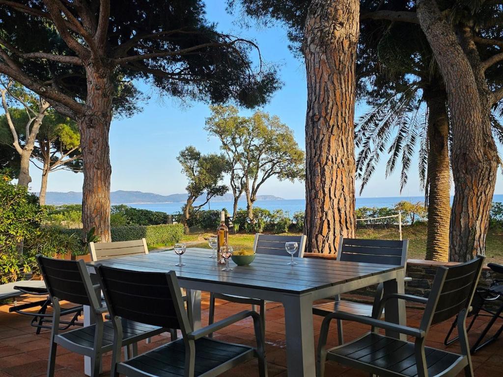 une table et des chaises sur un patio arboré dans l'établissement Villa Familiale Pied dans l'eau accès direct à la plage, à Cavalaire-sur-Mer