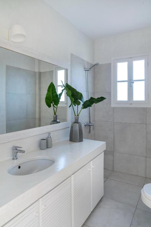 a white bathroom with a sink and a mirror at Villa Seascape, Beachfront Living in the Greek Riviera Porto Heli in Porto Heli