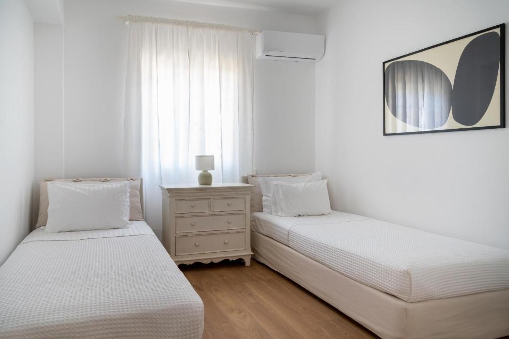 two beds in a bedroom with white walls and wooden floors at Villa Seascape, Beachfront Living in the Greek Riviera Porto Heli in Porto Heli