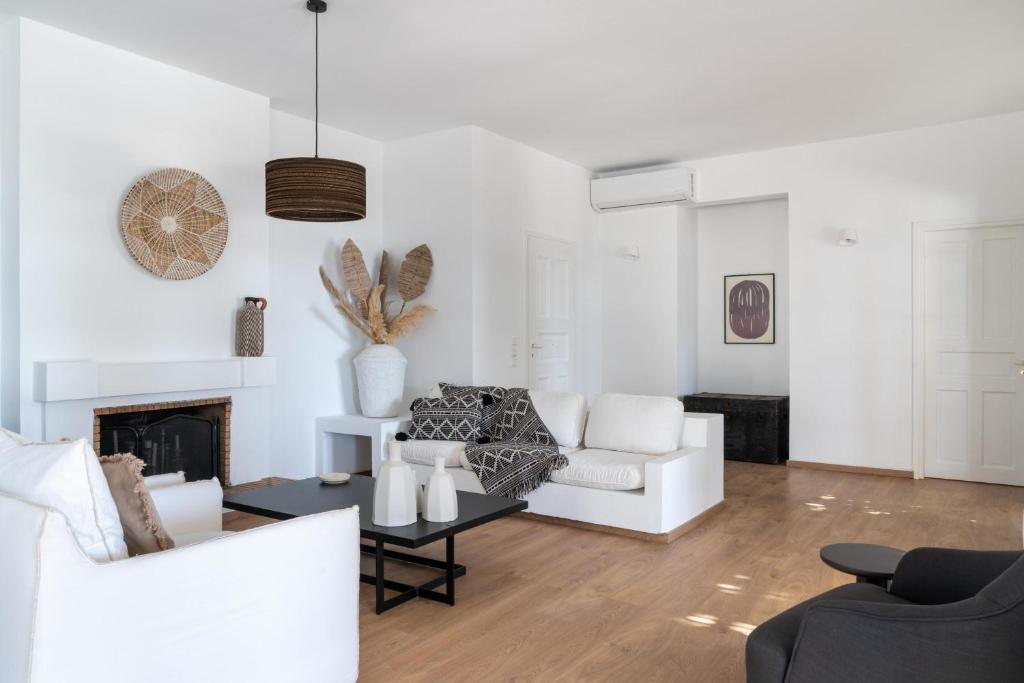 a living room with white furniture and a fireplace at Villa Seascape, Beachfront Living in the Greek Riviera Porto Heli in Porto Heli