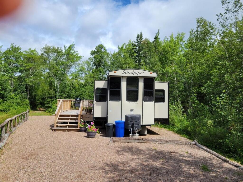 an rv parked in a gravel lot with trees at Aberdeen Hillview Retreat in Whycocomagh