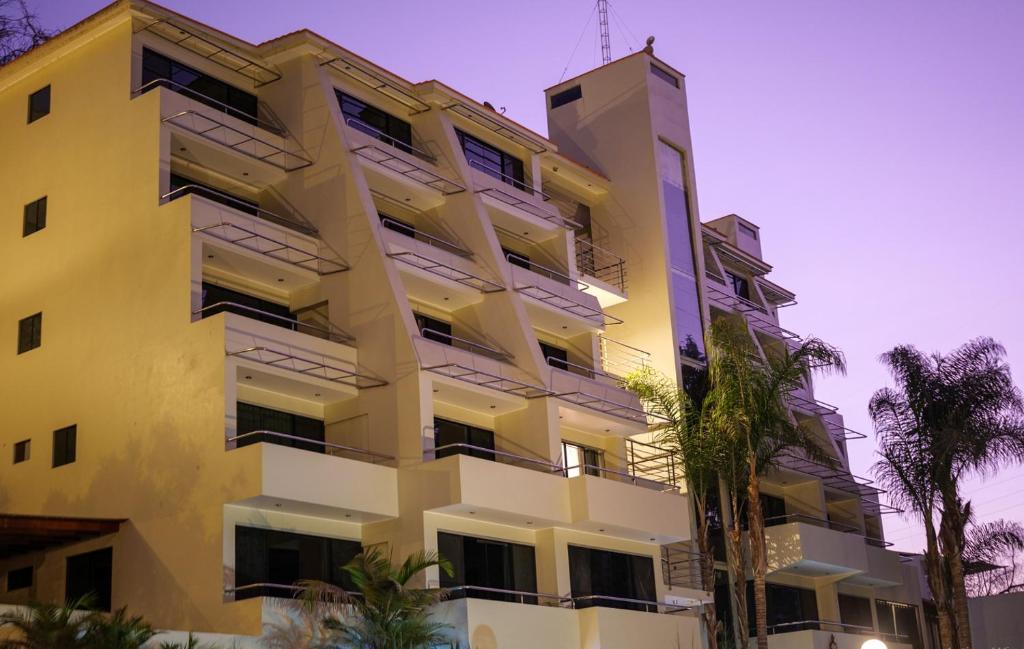 a tall yellow building with palm trees in front of it at Kankay Hotel y Centro de Convenciones in Cieneguilla