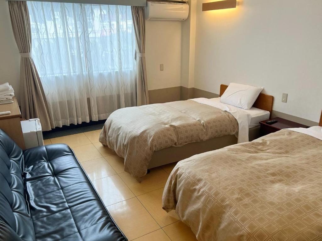 a hotel room with two beds and a couch at Hotel Yamadaso - Vacation STAY 41344v in Nago