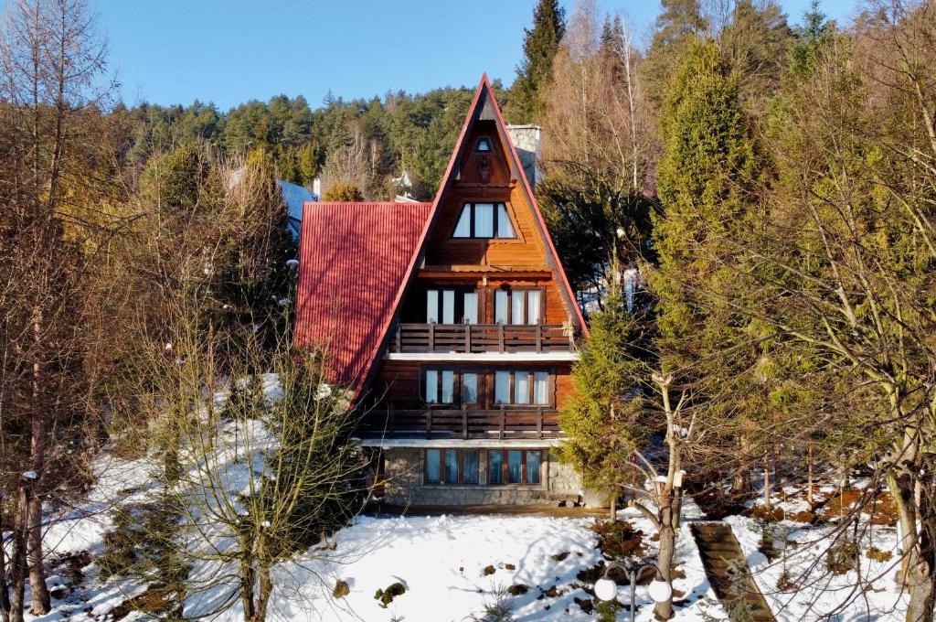 a house with a red roof in the snow at BUKOWA Jezioro Żywieckie Beskid Żywiecki Śląski Sauna Jacuzzi Kominek Morsowanie Tresna Żywiec Szczyrk in Tresna