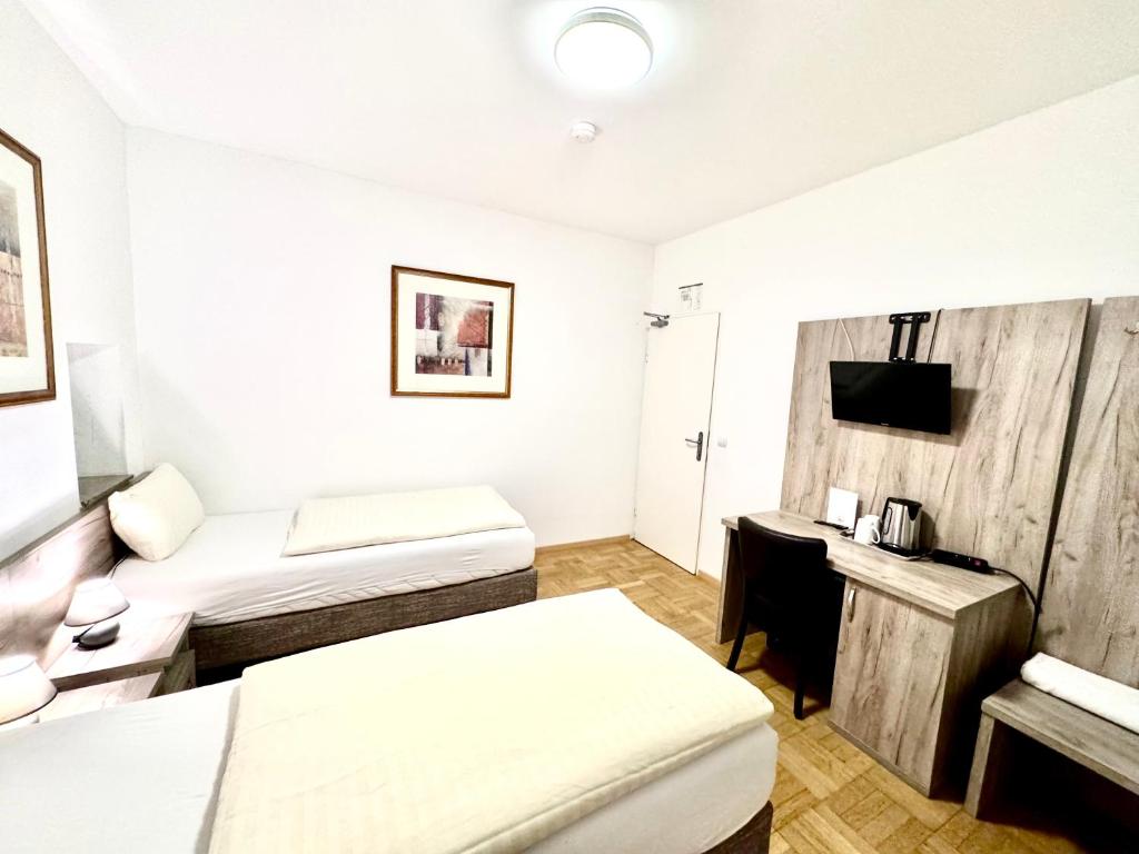 a hotel room with two beds and a desk at Hotel Soad in Salach