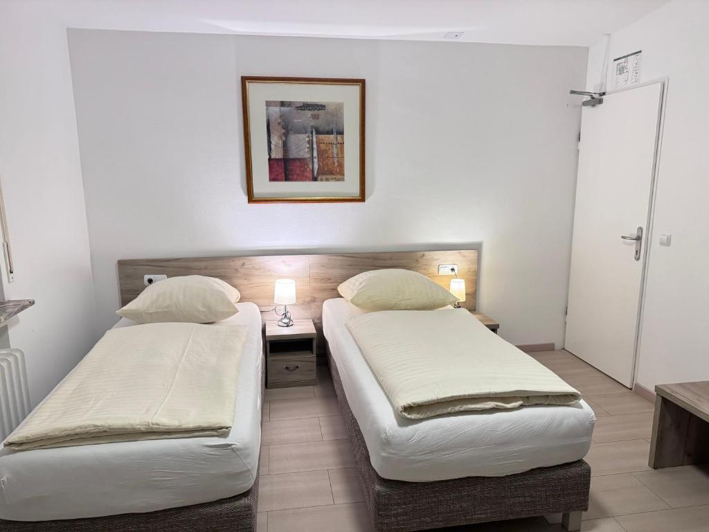 two beds in a room with a table and two lamps at Hotel Soad in Salach