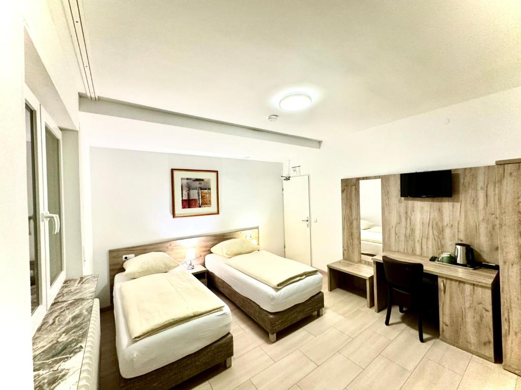 a hotel room with two beds and a desk at Hotel Soad in Salach