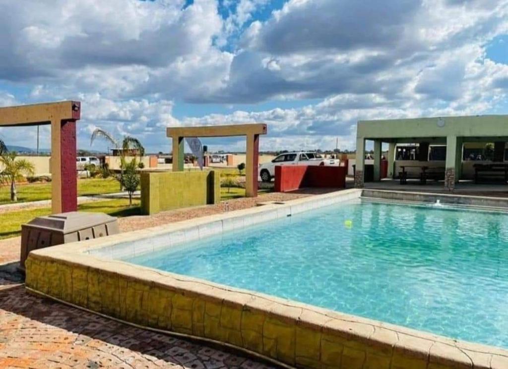 a swimming pool at a resort with a building at Rooibok Gardens in Mokopane