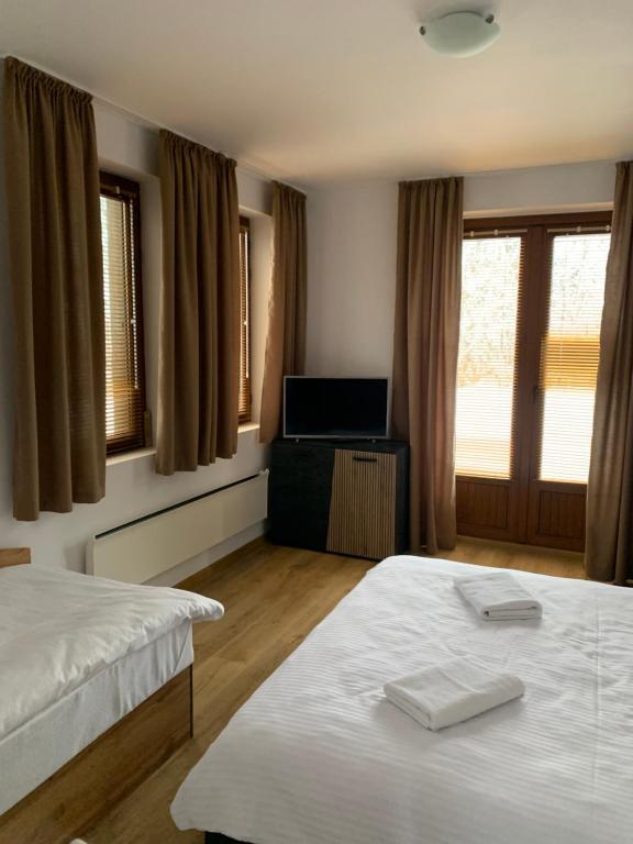 ein Schlafzimmer mit zwei Betten und einem Fernseher und Fenstern in der Unterkunft PAMPOROVO Raikovski lodge in Pamporowo