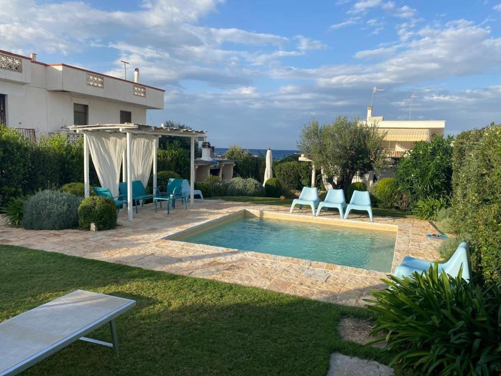 a backyard with a swimming pool and chairs and a house at Brezza sul Mare in Polignano a Mare