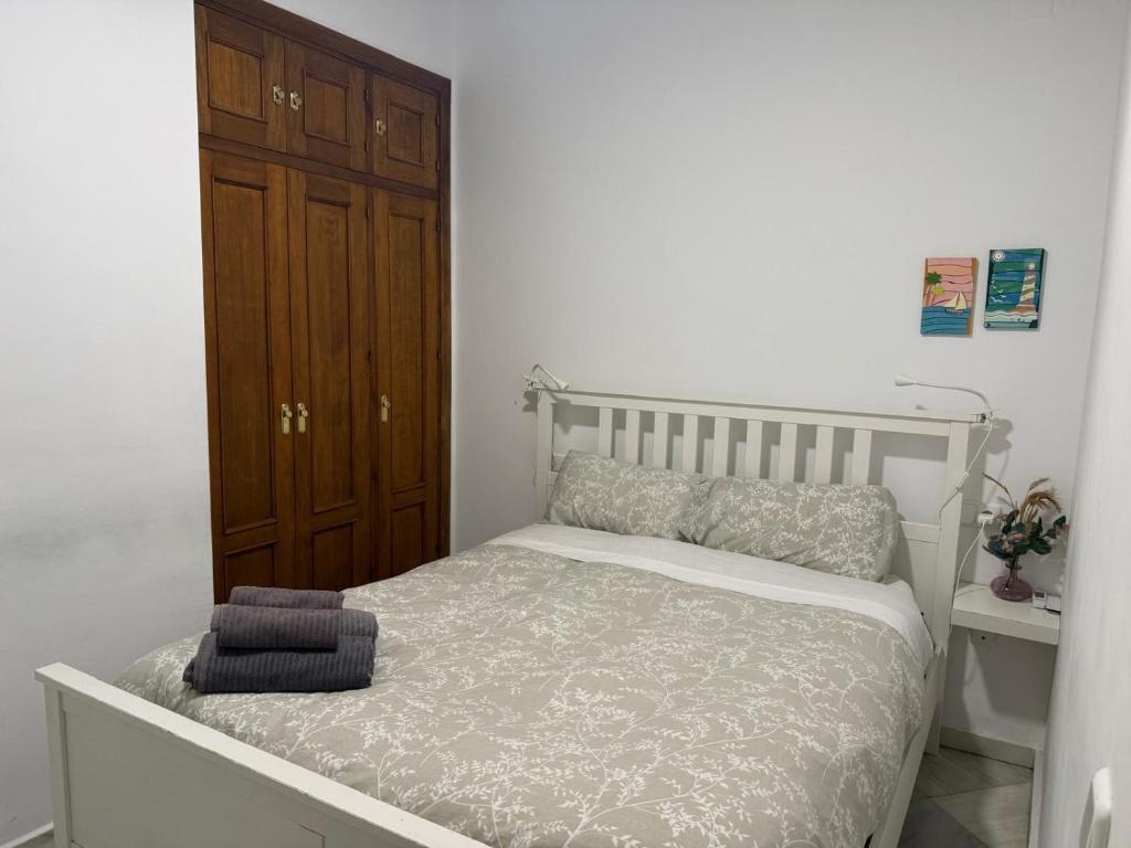 a white bedroom with a bed and a wooden cabinet at Apartamento Casa Palacio 1890. in El Puerto de Santa María