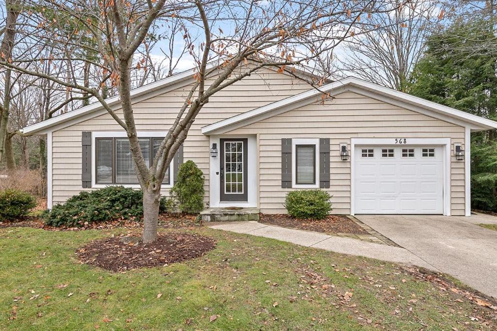 une petite maison avec un garage blanc et un arbre dans l'établissement Main Stay Cottage, à Saugatuck