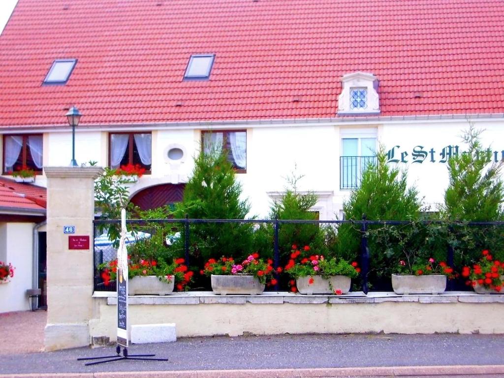 un edificio con tetto rosso con fiori in vasi di Hôtel Le Saint Martin a Bourg-Sainte-Marie