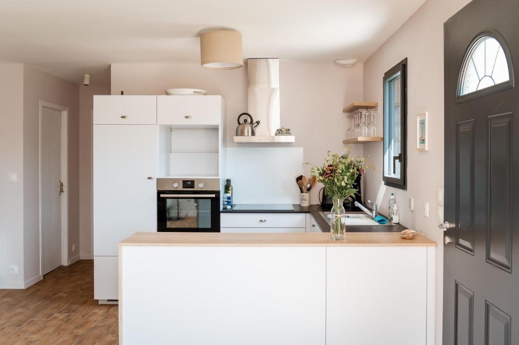 une cuisine avec des armoires blanches et un comptoir dans l'établissement Neues Haus nahe des Leuchtturms, à Penmarcʼh