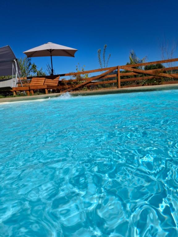 una piscina d'acqua con tavolo e ombrellone di Cabaña Refugio Magenta a Ñipas