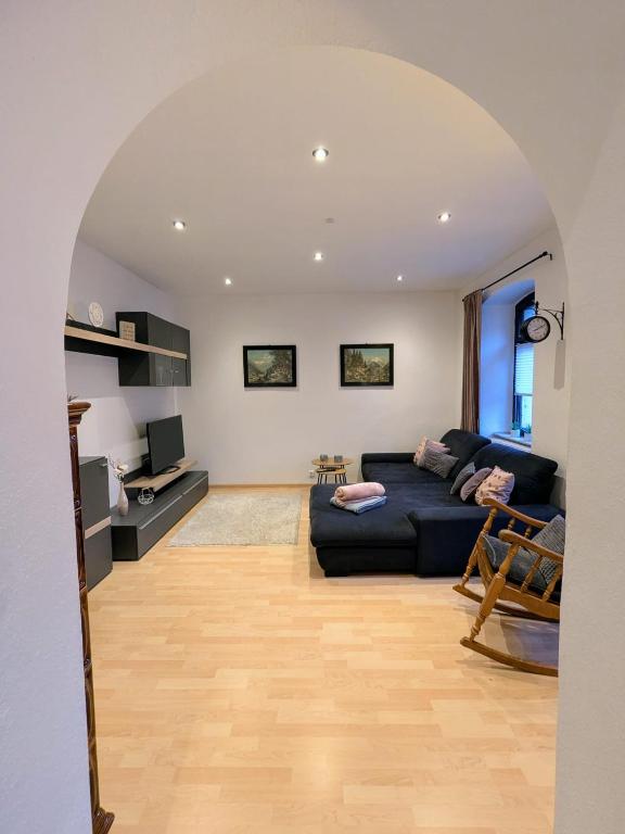 a living room with a black couch and a table at Ferienwohnung am Rabenauer Grund in Freital