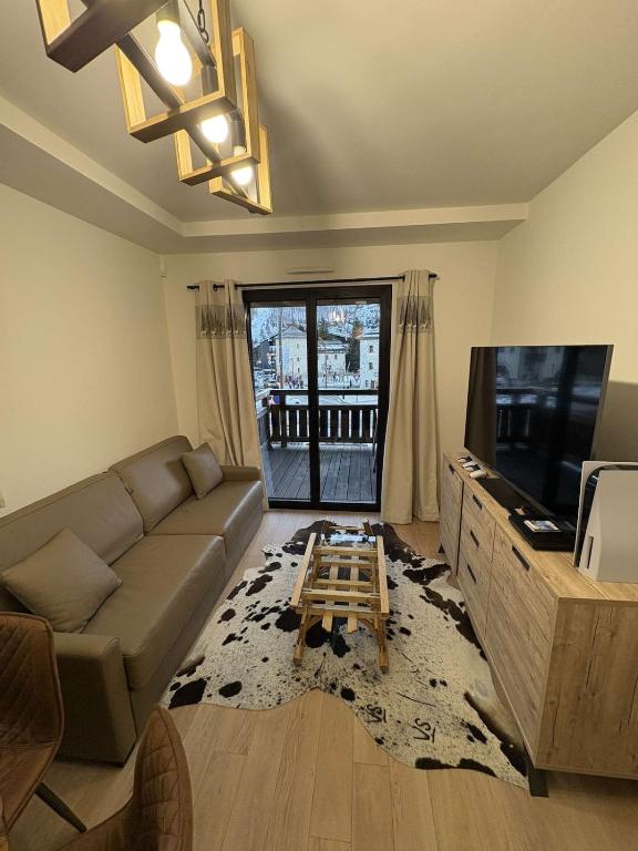 un salon avec un canapé et une télévision à écran plat dans l'établissement Apartment Le Monde des Neiges, à Saint-Étienne-de-Tinée