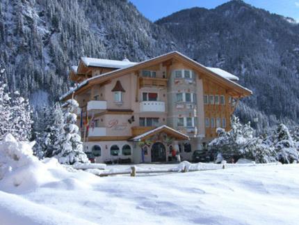 un grande edificio in mezzo a una montagna innevata di Alpenhotel Panorama a Campitello di Fassa