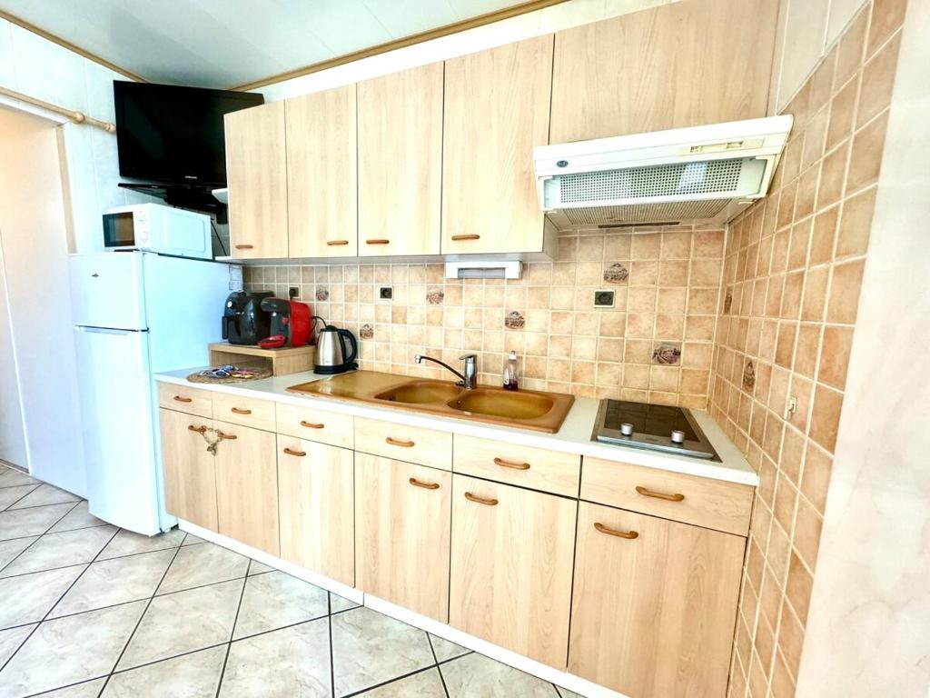 une cuisine avec un évier et un réfrigérateur blanc dans l'établissement La Mouette - Plein Centre Ville, à La Grande Motte