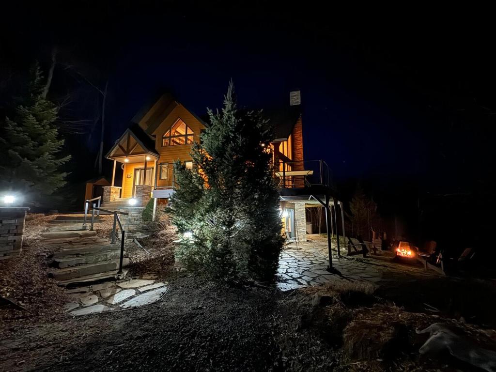 a house with a christmas tree in front of it at night at La Grande Ourse de Charlevoix in Petite-Rivière-Saint-François