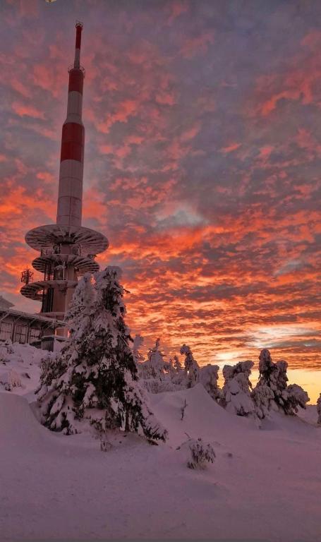 a lighthouse in the snow with a sunset in the background at Ellas Ferienhaus in Elbingerode