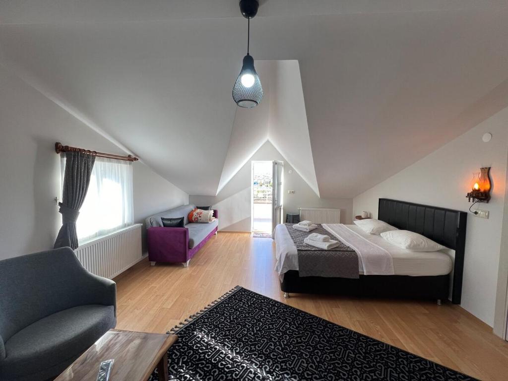 Un dormitorio con una cama, un sofá y una silla. en Ürgüp Manzaralı Ev Teras, en Ürgüp