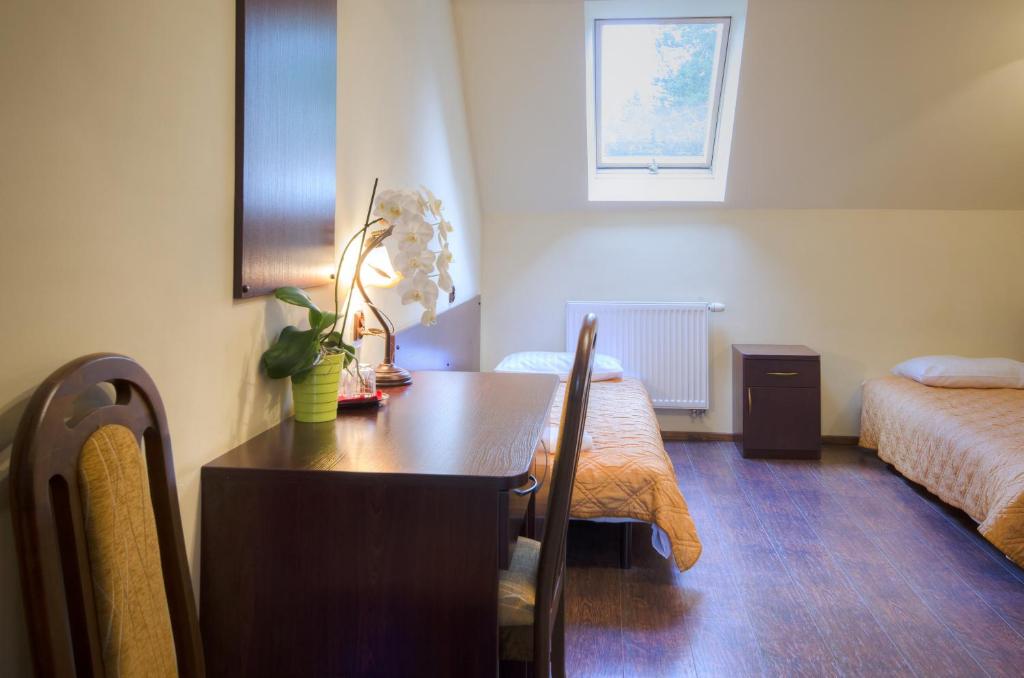 Room with twin beds, skylight, desk, and wooden flooring.