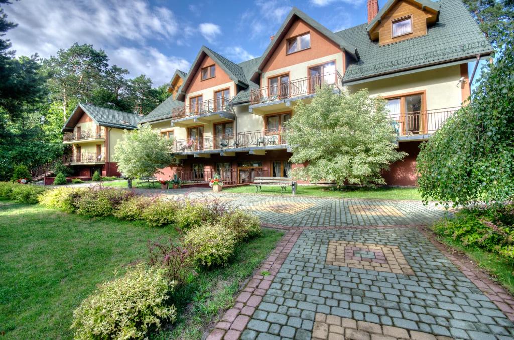 Hotel building with balconies, manicured gardens, and cobblestone path.