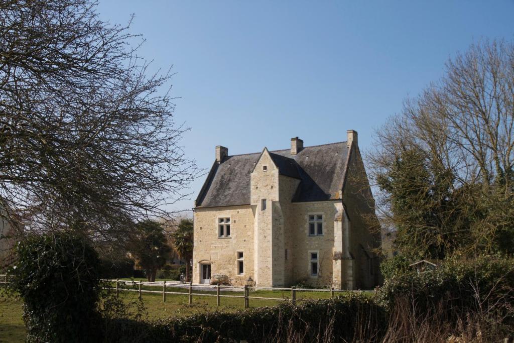 une ancienne maison en pierre dans un champ avec une clôture dans l'établissement Le Manoir du Pont Senot, à Noron-la-Poterie