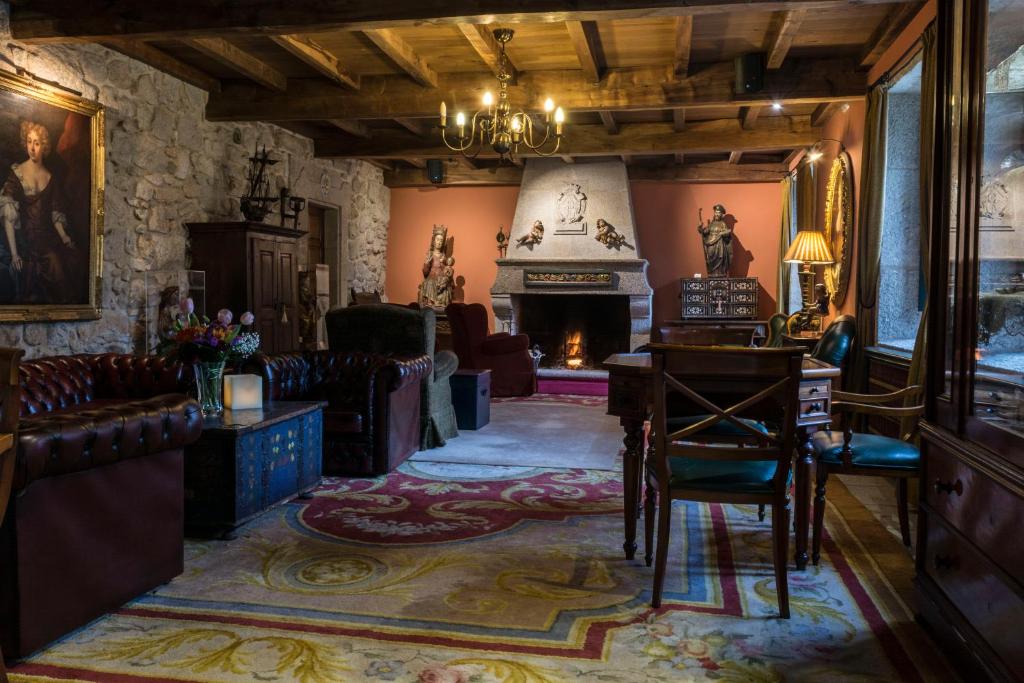 een woonkamer met een open haard en een tafel en stoelen bij Hotel Monumento Convento de San Benito in A Guarda