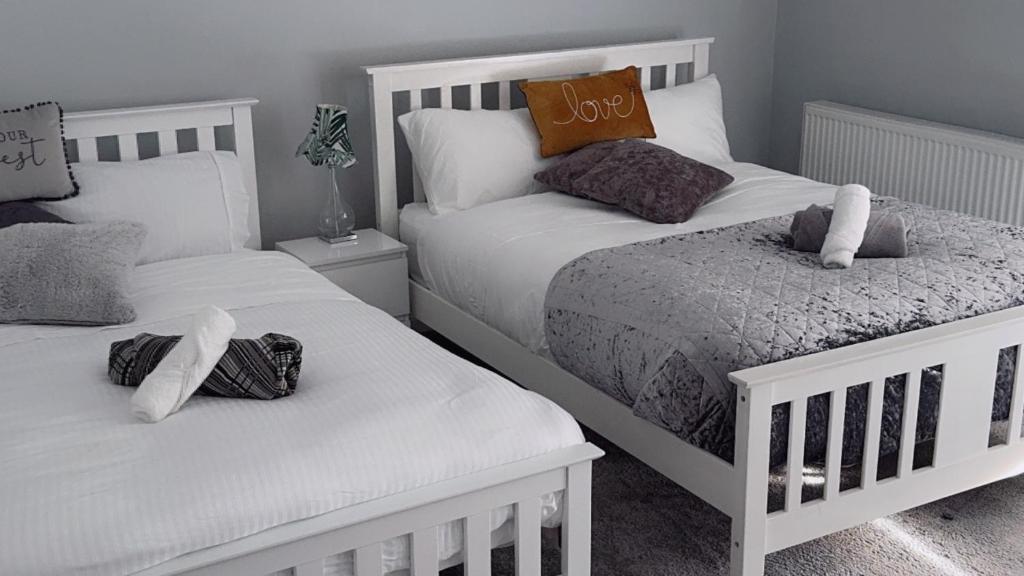 two white beds in a bedroom with white pillows at Tomelle Manchester in Manchester