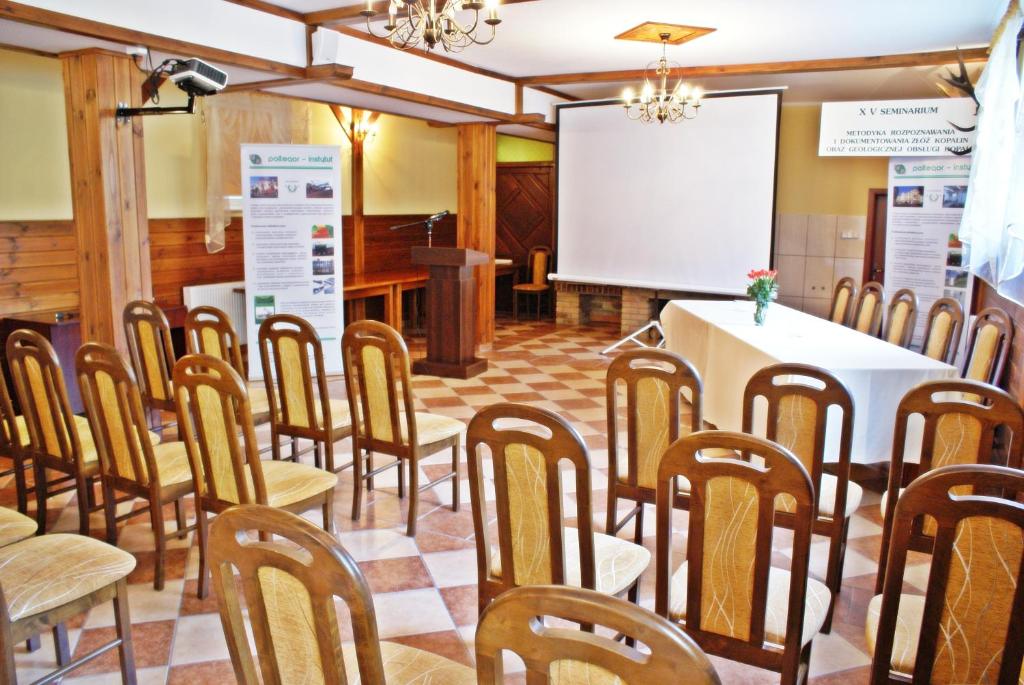 Conference room with arranged chairs, projector screen, and floral centerpiece.