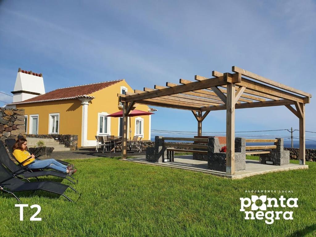 a woman sitting in a chair under a wooden pavilion at Casa das Lajes by Ponta Negra Azores in Caldeira