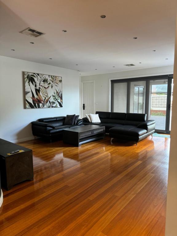 a living room with a black couch and a table at A luxury home in Oakleigh in Oakleigh