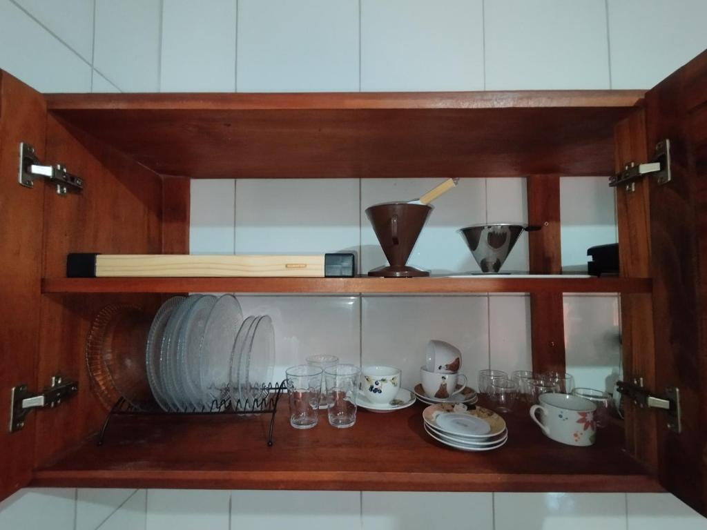 a wooden cabinet with dishes and glasses in it at Suíte Privativa in Paraty