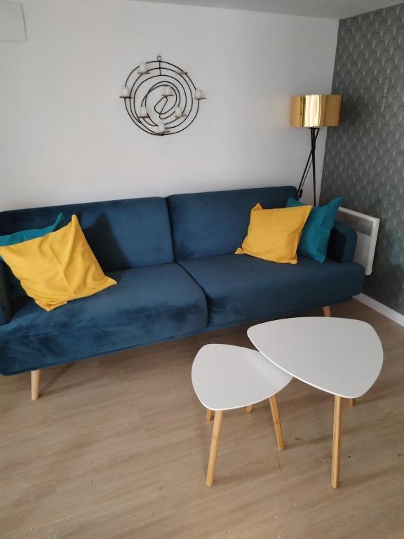 - un canapé bleu avec des oreillers jaunes et une table dans le salon dans l'établissement Charming Garden Floor studio, à Gagny