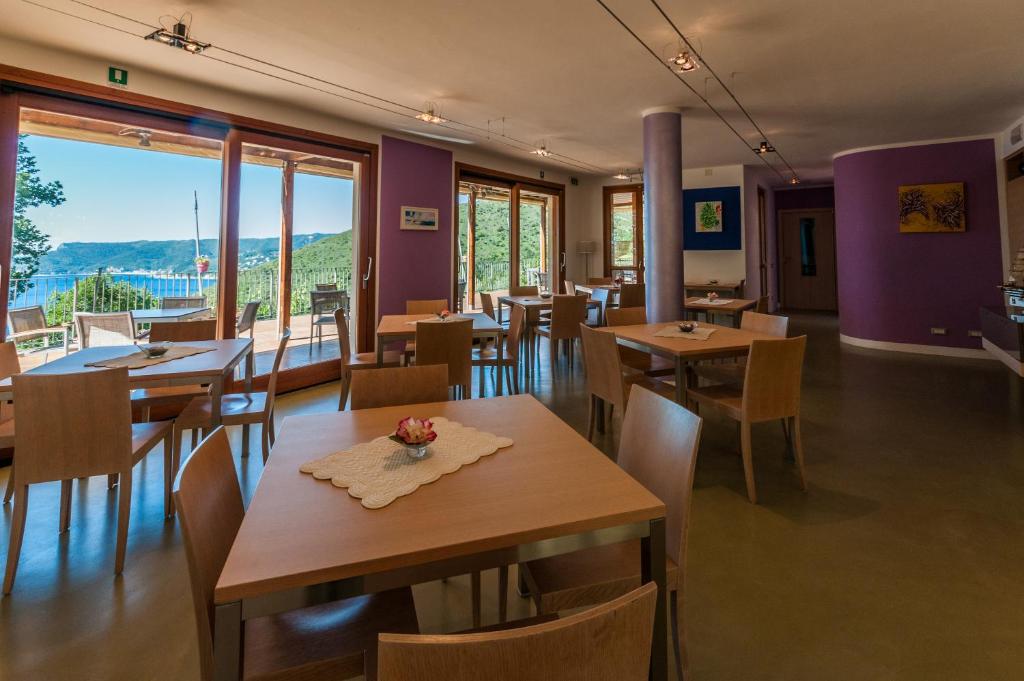 a restaurant with wooden tables and chairs and windows at Oroverde in Bergeggi
