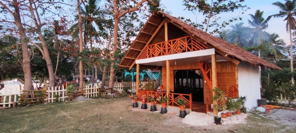 a small wooden house with a fence and trees at John and Novy Camotes Beach Bungalows in San Francisco