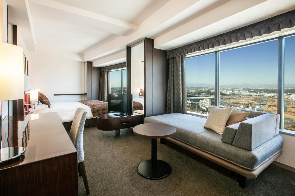a hotel room with a couch and a large window at Shin Yokohama Prince Hotel in Yokohama