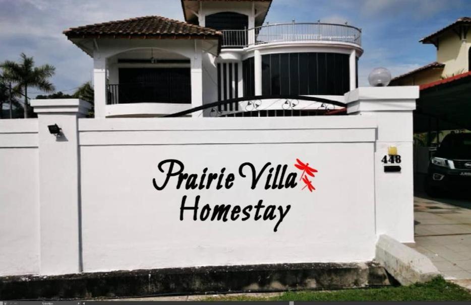 a white wall with a sign on it in front of a house at Prairie Villa Homestay in Lumut