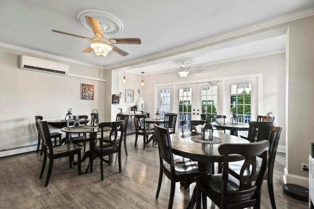 una sala da pranzo con tavoli, sedie e ventilatore a soffitto di The Inn At Ocean Grove a Ocean Grove