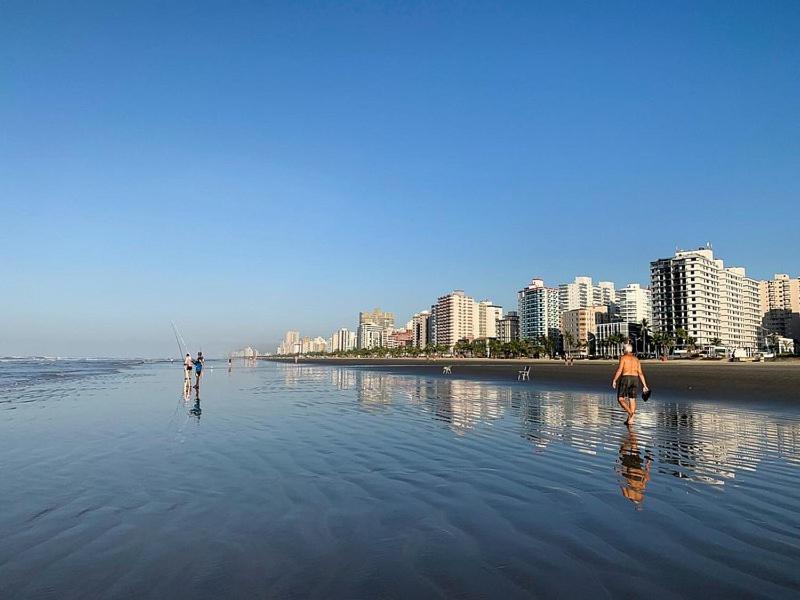 two people are standing in the water on the beach at apartamento próximo a praia condomínio ubirajara in Praia Grande