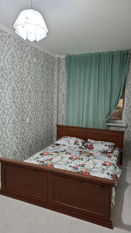 a bed with a wooden frame in a bedroom at Квартиры посуточно in Tridtsatʼ Let Kazakhstana