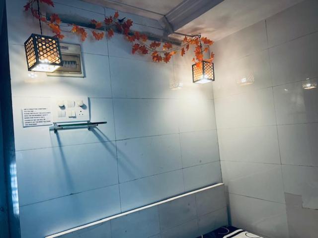 ein Badezimmer mit zwei Lichtern an einer gefliesten Wand in der Unterkunft Den near the sea in Mumbai
