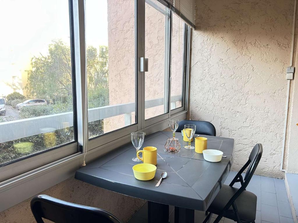 une table bleue avec des chaises et des verres ainsi qu'une fenêtre dans l'établissement Ste Maxime : Appt 2P, 4 couchages, piscine, parking - FR-1-226-556, à Sainte-Maxime