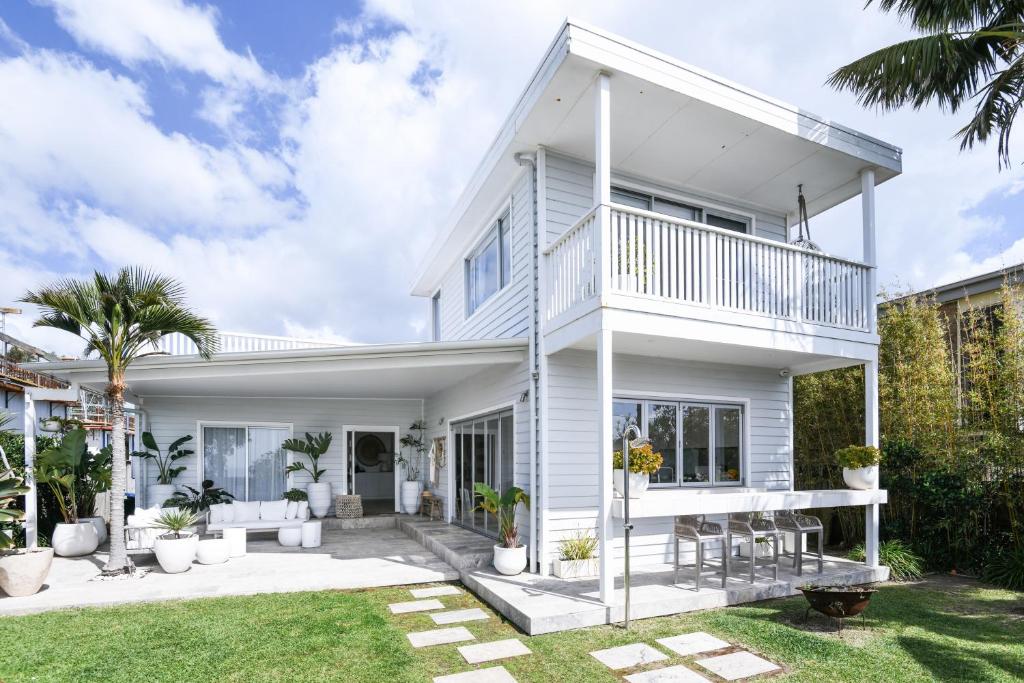 a white house with a balcony and a yard at Warriewood beach house in Mona Vale